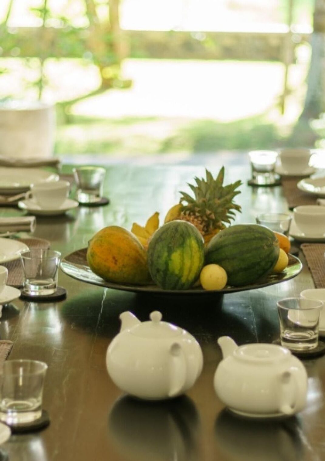 A table with a fruit plate, teapots, and cups.