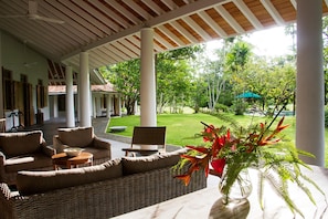 A covered outdoor seating area with wicker furniture and a potted plant.