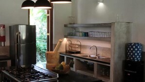 A modern kitchen with a central island, stainless steel appliances, pendant lighting, and a view of greenery outside. - Family House With Large Garden In A Peaceful Setting (Padinnoruwa)