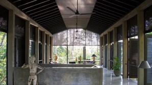 A modern interior with a central seating area, large windows, and a ceiling fan. - Historically Important Architecturally Stunning Hilltop Villa (Hapugala)