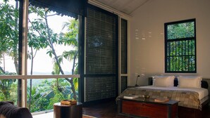 A bedroom with a large window, a bed, a bedside table, and a view of greenery outside. - Historically Important Architecturally Stunning Hilltop Villa (Hapugala)