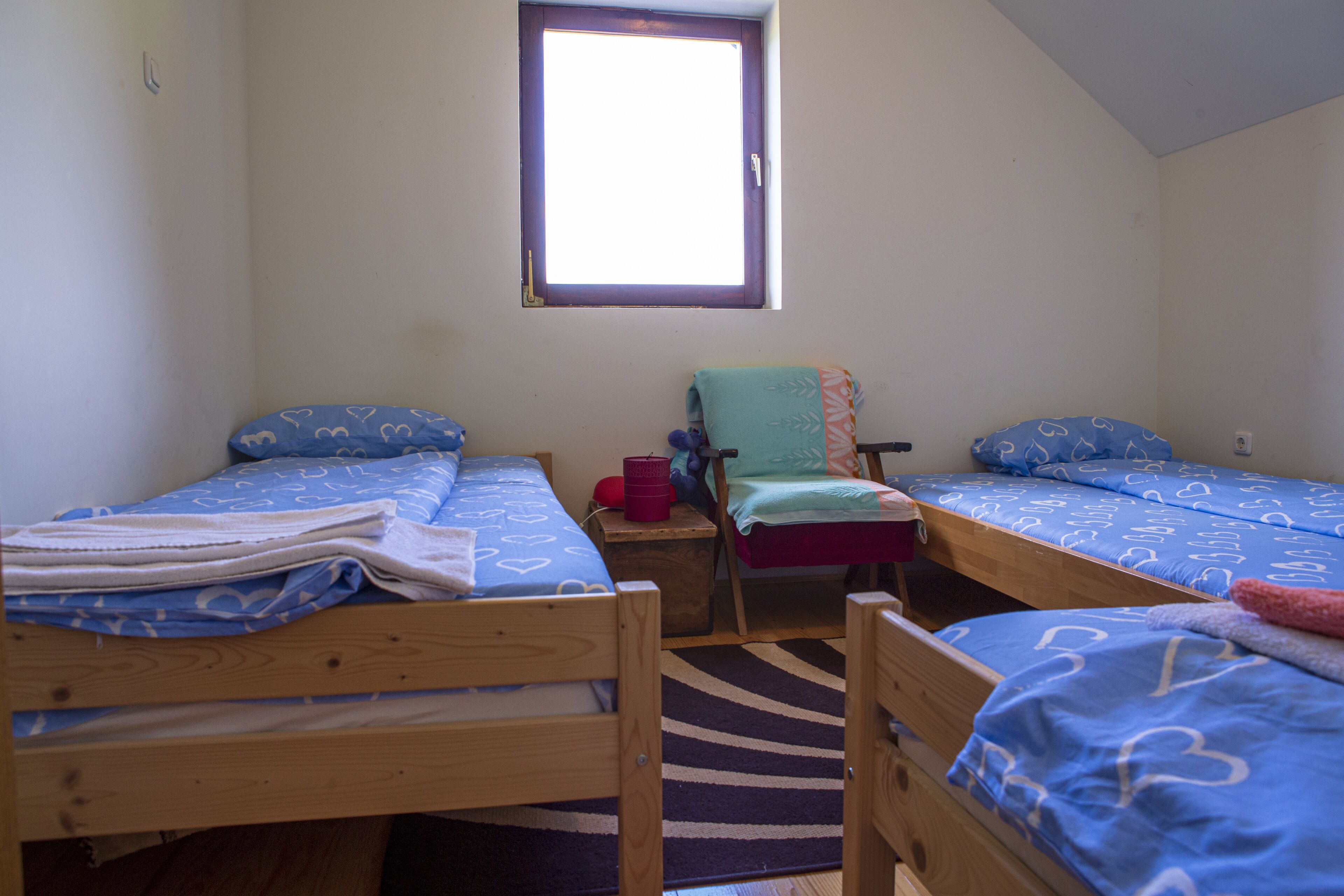 A room with two wooden beds, a small table, and a window.