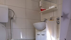 Un baño con inodoro, lavamanos, espejo y zona de ducha.