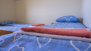 Una cama con ropa de cama azul y una manta rosa.
