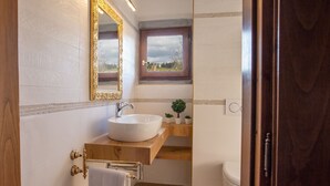 A bathroom with a white sink, gold-framed mirror, and a window with a view of trees. - Iris apartment (Città metropolitana di Firenze)