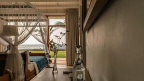A room with a bed, a table with a notebook, a bottle, and a view of the ocean. - Family Beach Villa Located On An Incredible Beach (Koggala)