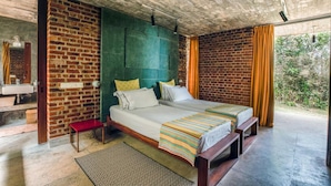 A modern bedroom with a brick wall, a large bed, a bench, and a view of greenery. - Sustainably Designed Villa Overlooking Indian Ocean (Tangalle)