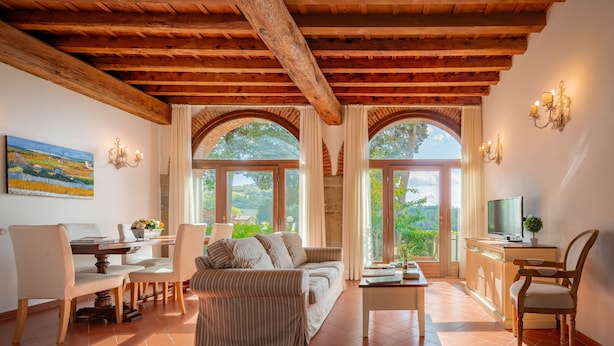 A spacious living room with a wooden ceiling, a sofa, a dining table with chairs, and a TV on a wooden cabinet. - Primula apartment (Città metropolitana di Firenze)