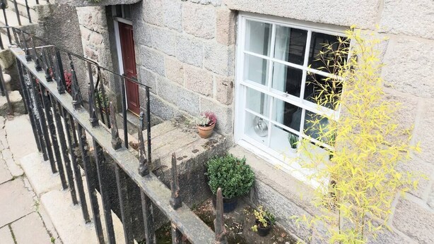 A stone building with a window, a door, and a small balcony with railings. - Granite Getaways - The Terrace Below (Aberdeen)