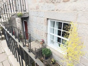 A stone building with a window, a door, and a small balcony with railings.