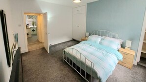 A bedroom with a bed, bedside tables, a wardrobe, and a ceiling light. - Granite Getaways - The Terrace Below (Aberdeen)