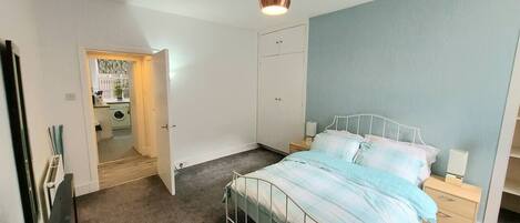 A bedroom with a bed, bedside tables, a wardrobe, and a ceiling light.