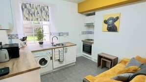 A compact living space with a kitchenette, a sofa, and a dining area. - Granite Getaways - The Terrace Below (Aberdeen)