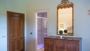 Un pasillo con una puerta de madera, una puerta de cristal que da al baño y un aparador con espejo.