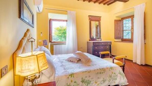 Un dormitorio con una cama, un escritorio con lámpara, un aparador y una ventana.