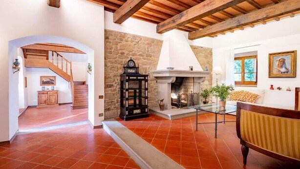Amplia sala de estar con chimenea, una escalera y un comedor.