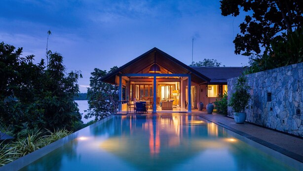 A modern house with a swimming pool, surrounded by lush greenery and a stone wall. - Elevated Villa Overlooking Tranquil Koggala Lake (Ahangama)