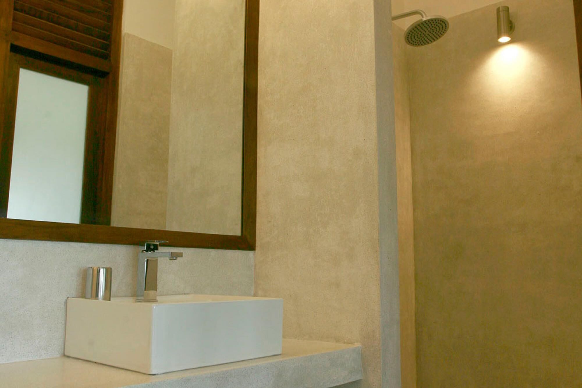 A bathroom with a white sink, a mirror, and a shower area.