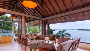 An open-plan living area with a view of a lake, furnished with sofas, chairs, and a coffee table. - Elevated Villa Overlooking Tranquil Koggala Lake (Ahangama)