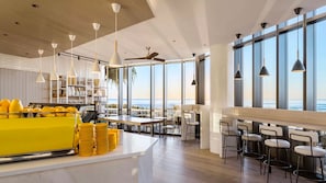 Une cuisine moderne avec un coin bar, de grandes fenêtres et une vue sur l’océan.
