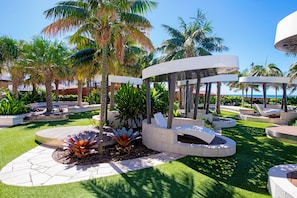 Un jardin aménagé avec des palmiers, un kiosque et un espace piscine.
