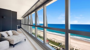 Un dormitorio moderno con un ventanal grande que da a una playa y al océano.
