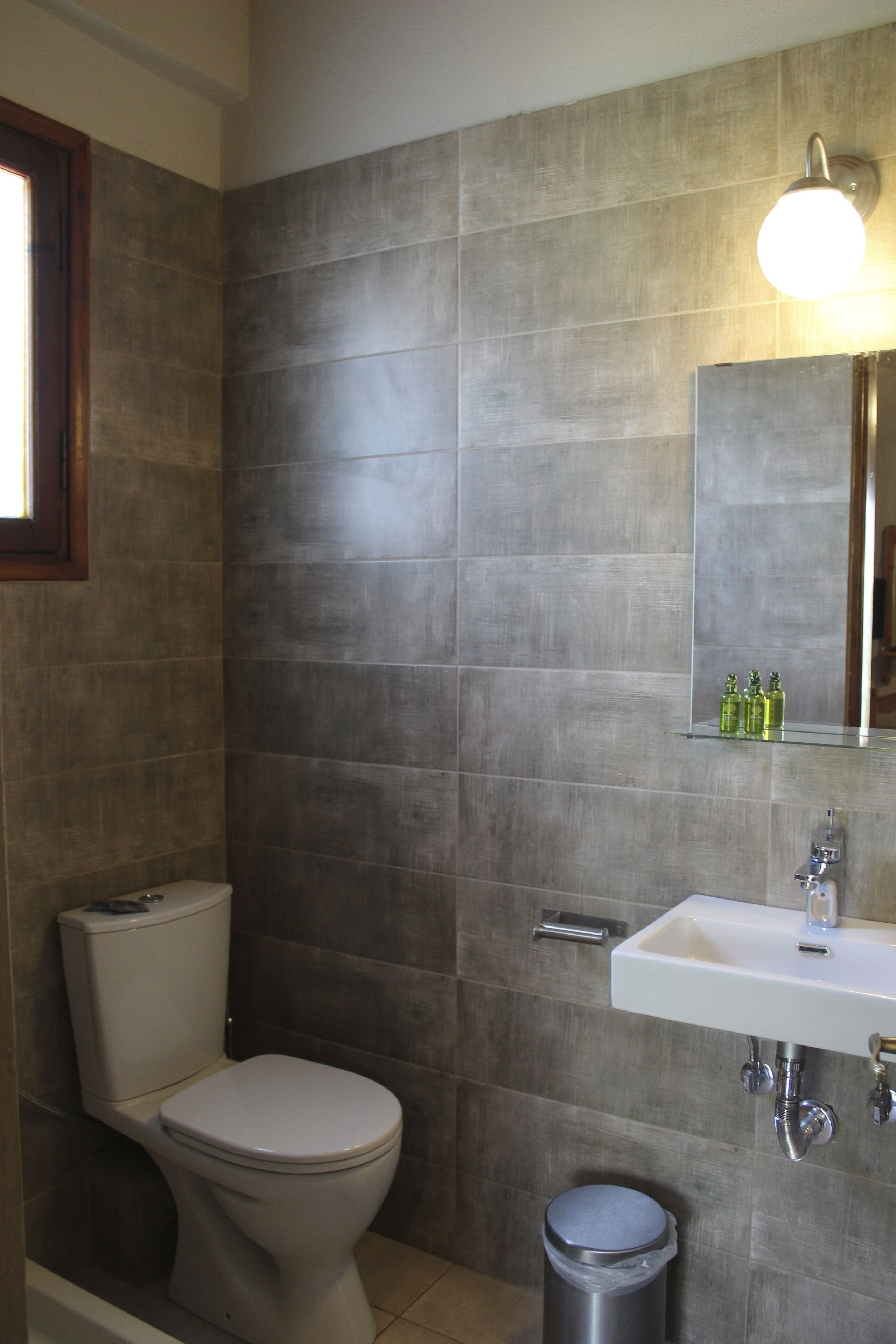Un baño con inodoro, lavamanos y cubo de basura.
