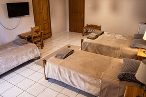 A hotel room with two beds, a desk, a chair, a TV, and a wardrobe.