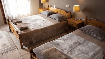 A hotel room with two beds, each with a wooden headboard, a bedside table, and a lamp.