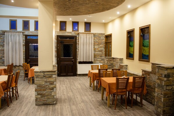 A restaurant with stone walls, wooden tables, and chairs.
