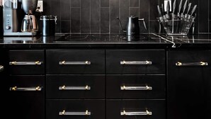 Et moderne køkken med sorte skabe, rustfrie hvidevarer og en backsplash af sorte fliser.