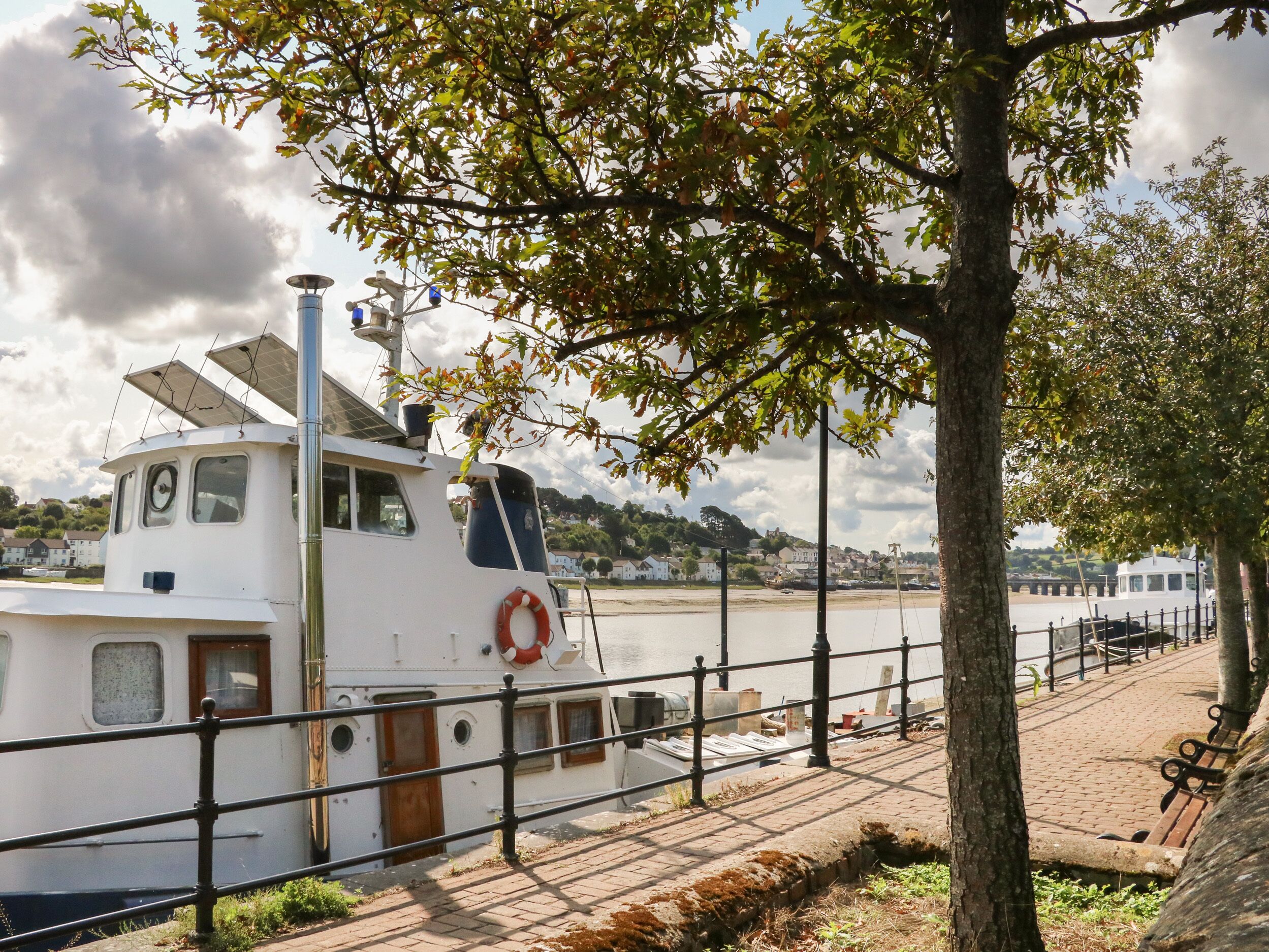 A white boat docked at a pier with a lifebuoy attached to the side.
