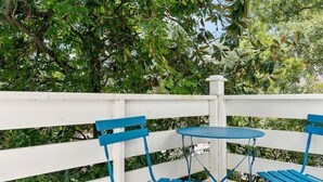 A wooden deck with a white fence and blue metal chairs and table.