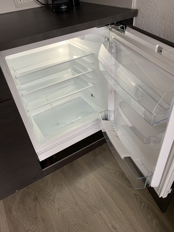 An open refrigerator with clear shelves and a black countertop.