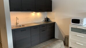 A compact kitchen with dark cabinets, a white countertop, a sink, a toaster, and a microwave. - Modern apartment, right on a lake in Winterberg-Niedersfeld (Winterberg)