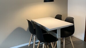 A dining area with a white table, black chairs, and a hanging black pendant light. - Modern apartment, right on a lake in Winterberg-Niedersfeld (Winterberg)