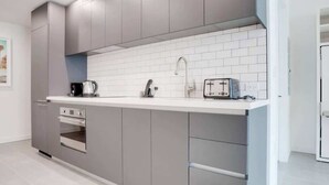 A modern kitchen with grey cabinets, a white countertop, and a built-in oven. - Modern & newly built studio Pool|Gym|Restaurant| (Miami)