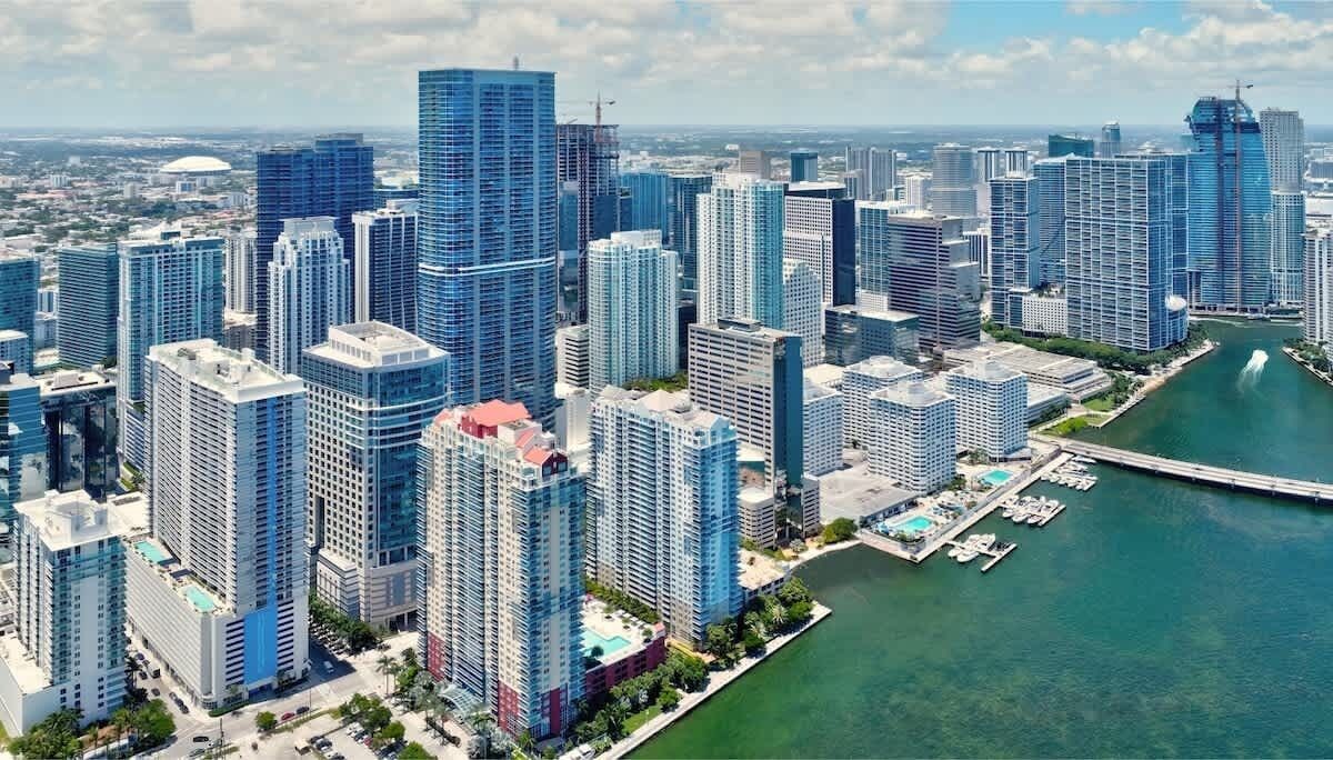 A high-rise urban area with modern skyscrapers, a marina with boats, and a clear view of the water.