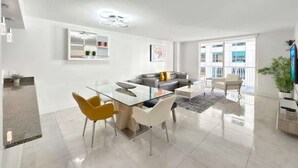 Un salon moderne avec une table à manger en verre, un canapé et un téléviseur.