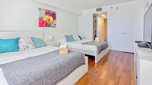 A modern hotel room with two beds, a TV, and a painting on the wall. - Ocean & City Views Lux Miami Brickell | Sleeps 5 (Miami)