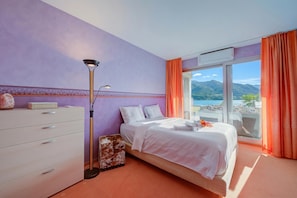 Un dormitorio con cama, cómoda, lámpara y vistas al mar.