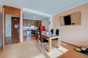 Una cocina moderna con armarios de madera, un refrigerador rojo y un comedor con mesa y sillas de madera.