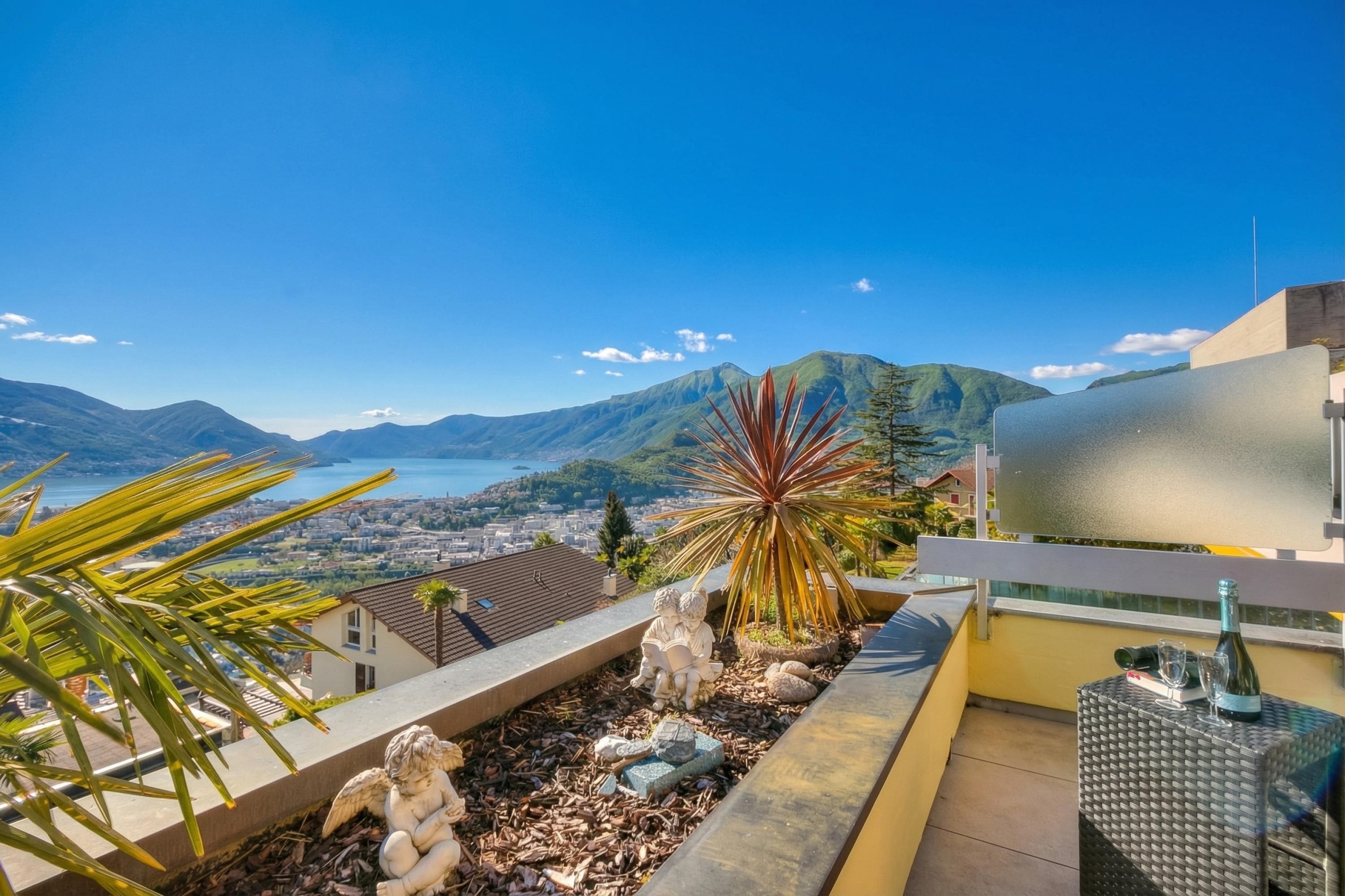 A balcony with a view of a city, mountains, and a body of water.