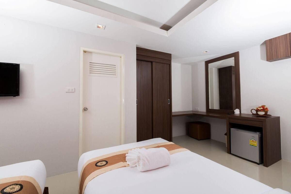 Una habitación de hotel con cama, escritorio, espejo y televisor.
