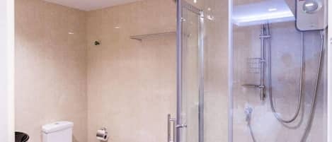 A modern bathroom with a glass-enclosed shower, a toilet, and a sink.