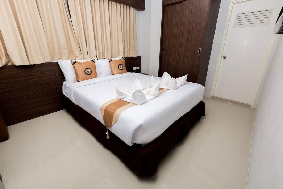Una habitación de hotel con una cama bien hecha, un cabecero de madera y una puerta cerrada.