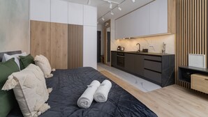 Un dormitorio moderno con una cama grande, un armario empotrado y una kitchenette.