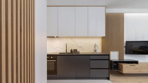 Una cocina moderna con horno integrado, un lavamanos y un televisor.