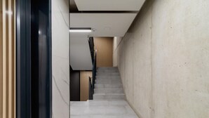 Una escalera moderna de diseño minimalista, con un muro de hormigón a un lado y paneles de madera al otro.