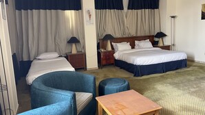 Una habitación de hotel con una cama, dos mesitas de noche, un escritorio, una silla y un sofá.